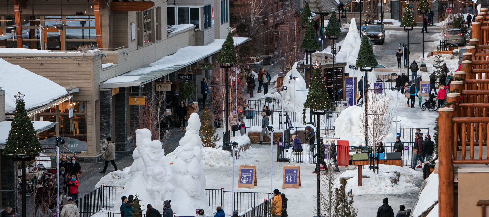An image showing the snow sculpture exhibition with the snow-capped mountain in the background at SnowDays 2022 at the Town of Banff on a winter day.